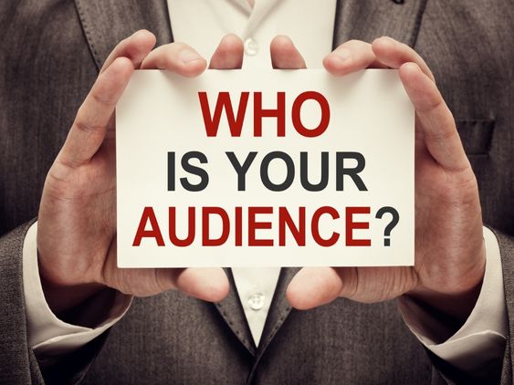 Person in a brown suit holds a card that says, "Who is your audience?"